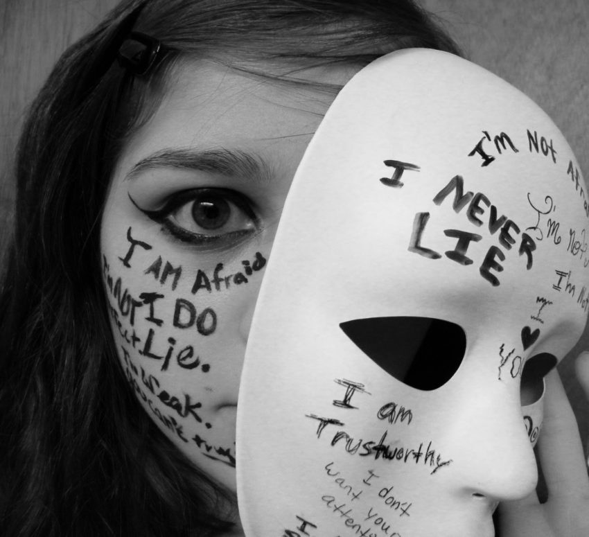 woman with writing on her face taking off a mask